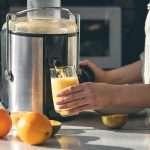 woman-makes-orange-juice-home-kitchen-with-electric-juicer