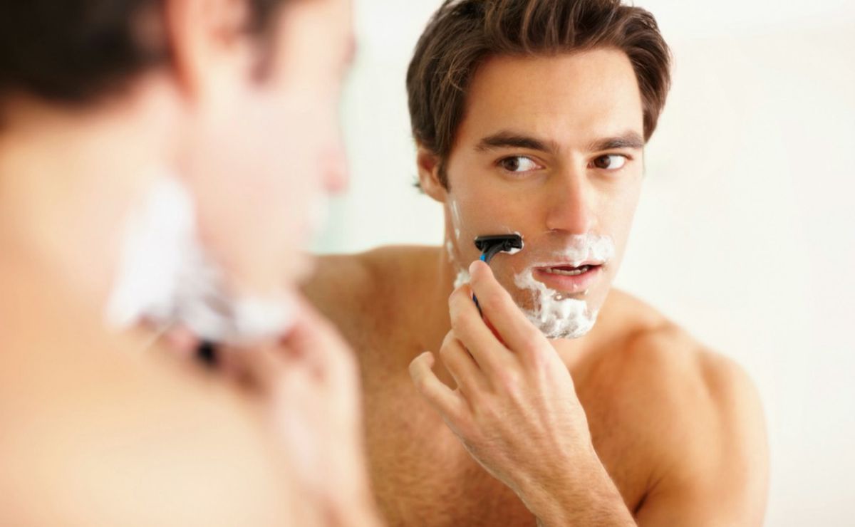 Un hombre se afeita frente a un espejo espuma de afeitar