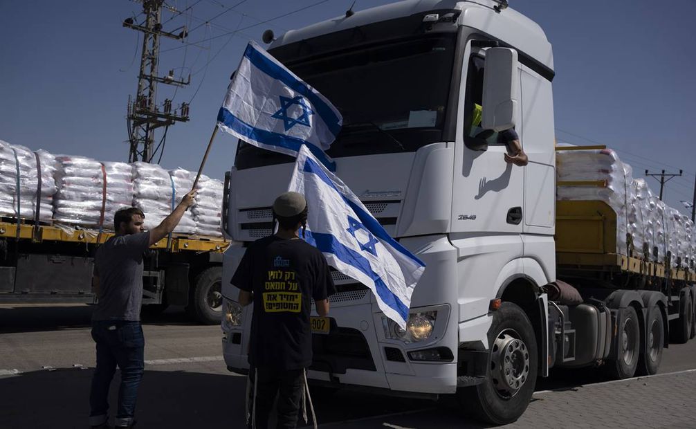Personas con banderas israelíes frente a camiones dirigidos a llevar ayuda humanitaria a la Franja de Gaza. Foto: AP