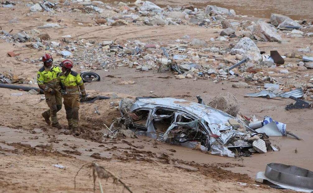 Los trabajadores de rescate pasan junto a un automóvil destruido medio enterrado después de las inundaciones en Paiporta, cerca de Valencia, España, el domingo 3 de noviembre de 2024. Foto: AP