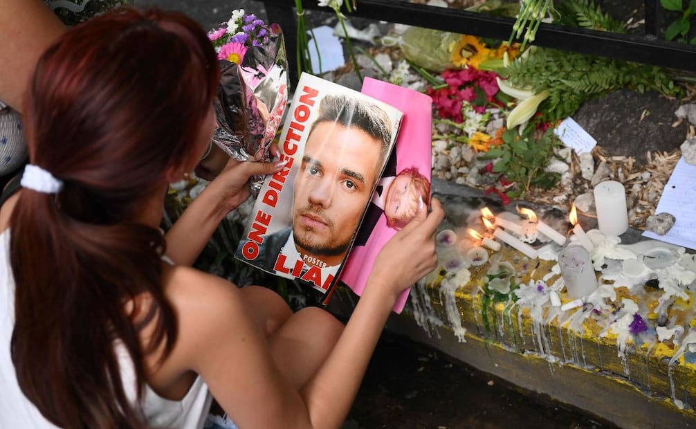 Una fan sostiene una revista con una foto del cantante británico Liam Payne mientras le rinde homenaje afuera del hotel donde murió en Buenos Aires. Foto: AFP.