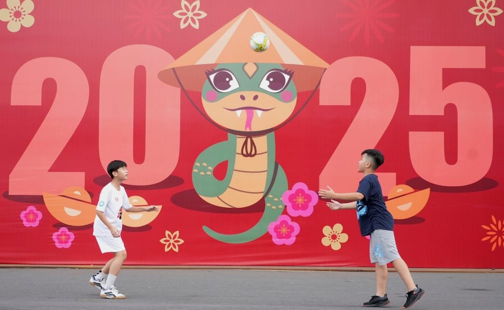 Dos niños juegan al fútbol ante un cartel celebrando el Año Nuevo 2025 en la ciudad de Ho Chi Minh, Vietnam, el martes 31 de diciembre de 2024. (AP Foto/Hau Dinh)