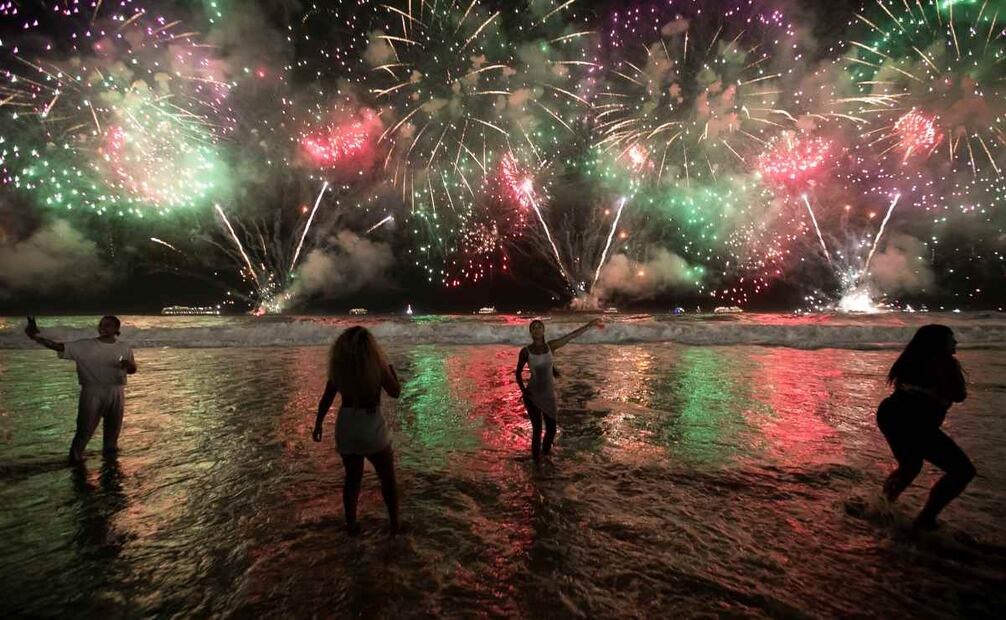 La gente celebra el inicio del Año Nuevo mientras los fuegos artificiales iluminan la playa de Copacabana en Río de Janeiro, Brasil, la madrugada del lunes 1 de enero de 2024. Foto: AP