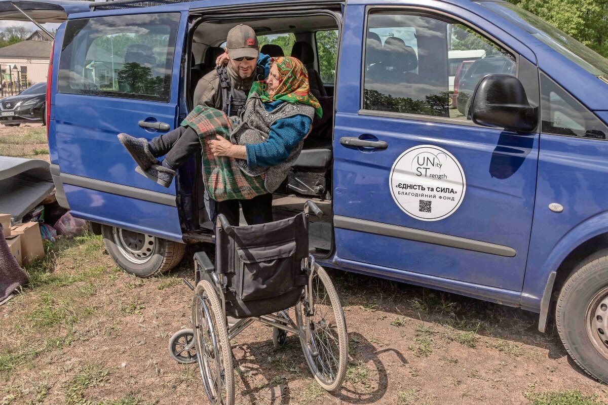 Un voluntario ayuda a una ucraniana en Vovchansk, distrito al que arribó desde la región de Kharkiv. Foto: Roman Pilpey AFP