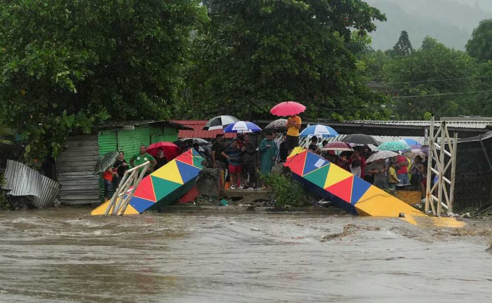 La gente se encuentra junto a un puente peatonal que se derrumbó debido a las inundaciones causadas por las lluvias provocadas por la tormenta tropical Sara en San Pedro Sula, Honduras. Foto: AP