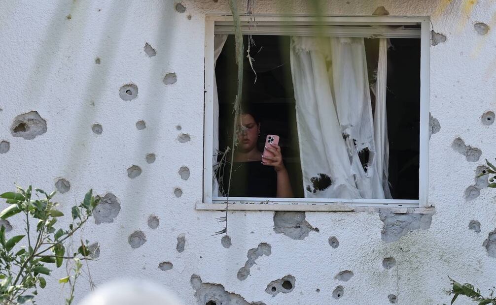 Una mujer que utiliza un teléfono móvil inspecciona los daños en el lugar de un ataque con misiles contra un barrio residencial en Kiryat Bialik, al norte de Israel. Foto: EFE