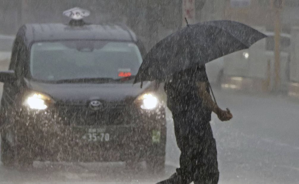 Una persona cruza una calle protegida por un paraguas durante un intenso aguacero, en Miyazaki. Foto: AP