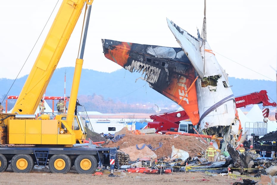 Una grúa levanta la sección de cola durante la operación de salvamento del avión Boeing 737-800 de Jeju Air que se estrelló y estalló en llamas en el Aeropuerto Internacional de Muan. Foto: AFP