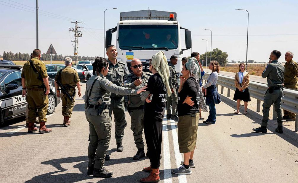 Los guardias fronterizos israelíes hablan con manifestantes de derecha que bloquean la carretera a los camiones jordanos que transportan suministros de ayuda humanitaria que llegan al lado israelí del cruce fronterizo de Kerem Shalom con la Franja de Gaza. Foto: AFP
